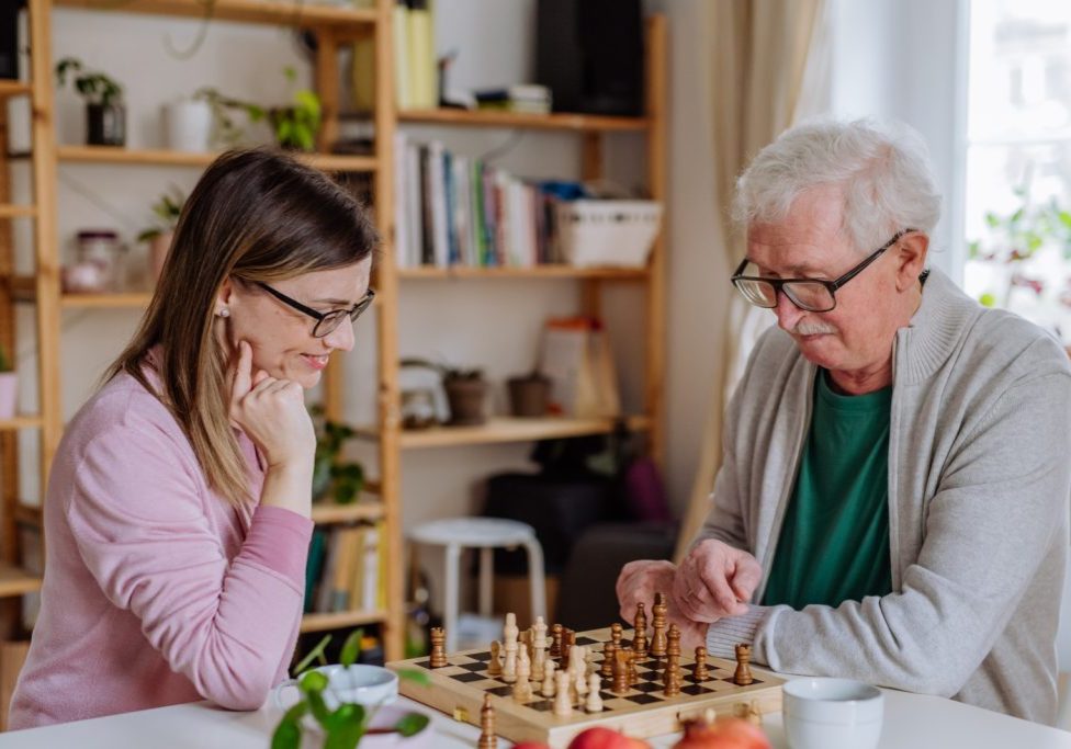 Elderly couple playing chess at home.